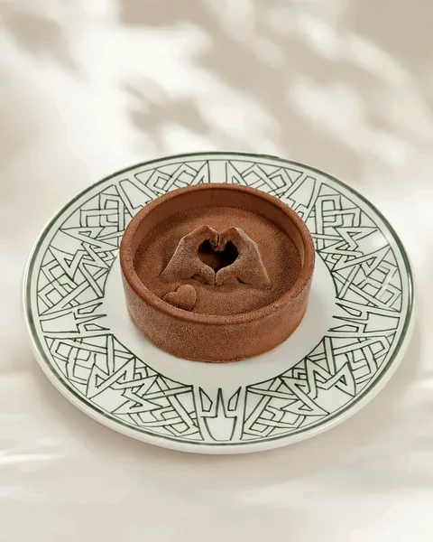 Tartelette au chocolat surmontée de mains en cœur en relief